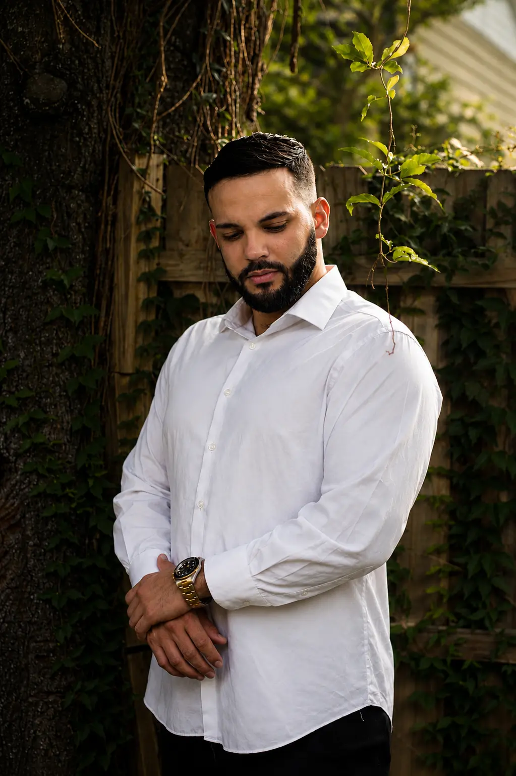 Portrait — man in white shirt by ivy-covered fence